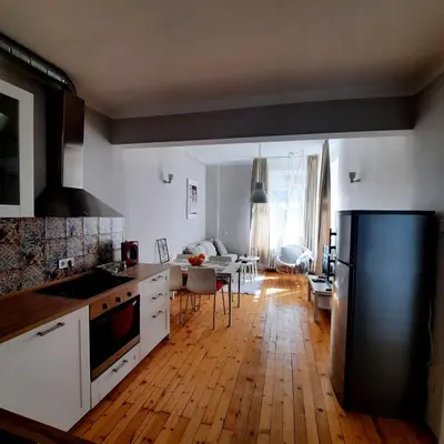 a kitchen with white cabinets and a black refrigerator at Cozy & Stylish apartment in the heart of Sofia in Sofia