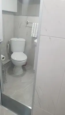 a white bathroom with a toilet and a sink at Допълнителна къща за гости Ози 2 in Ovchartsi