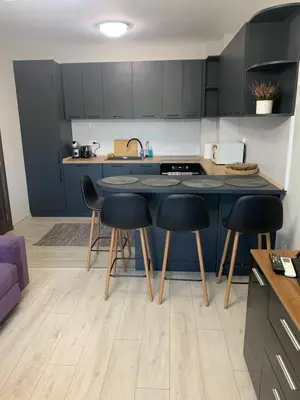 a kitchen with black cabinets and a table and stools at Pazardzhik suite home in Pazardzhik