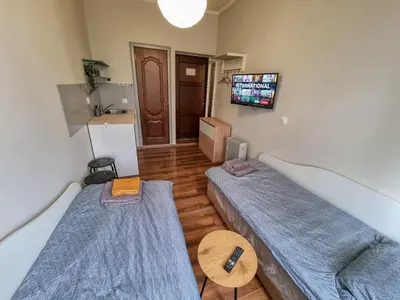 a room with two beds and a tv on the wall at Charming Studio in Sofia Center in Sofia