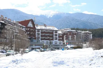 a snow covered parking lot in front of a building at Panorama Bansko in Bansko