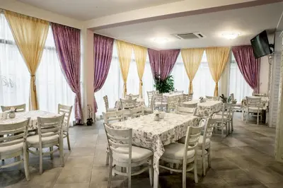 a restaurant with white tables and chairs and purple curtains at Astrea Deluxe in Hisarya