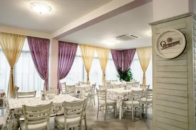 a restaurant with white tables and chairs and purple curtains at Astrea Deluxe in Hisarya