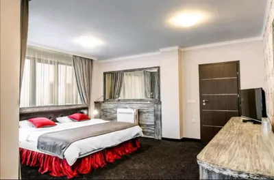a hotel room with a large bed with red pillows at Astrea Deluxe in Hisarya