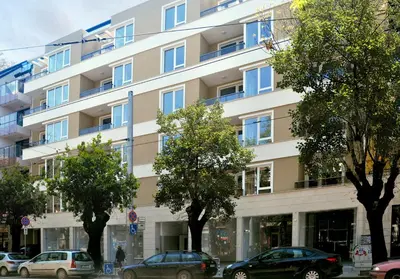 a large building with cars parked in front of it at Contemporary Charm in Old Sofia in Sofia