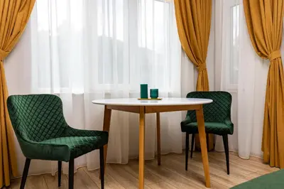 a table and two green chairs in a room with a window at Kapana Guest House on Central Pedestrian street with Parking included in Plovdiv