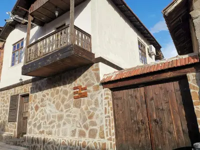 a building with a wooden door and a balcony on it at Къща за гости Старата череша село Раждавица in Rzhdavitsa