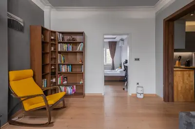 a living room with a yellow chair and a book shelf at The Honeycomb Hideaway by Flat Mаnager in Sofia