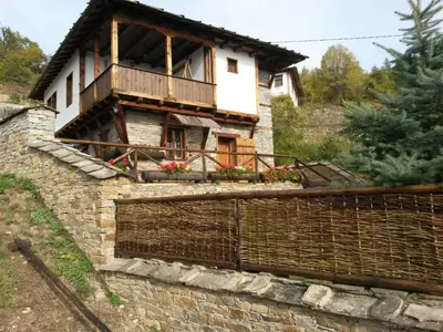 a house with a balcony on top of a brick wall at Leshten Valentin's House in Leshten