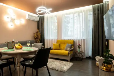 a living room with a table and a yellow couch at Какао Апартамент Велинград in Velingrad