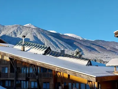 a building with snow covered mountains in the background at Piringolf apartment in Razlog