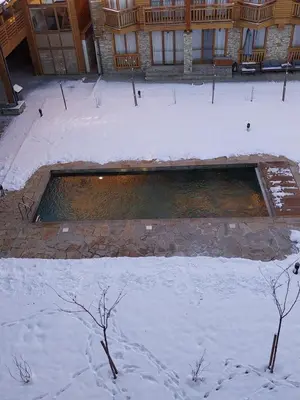a swimming pool covered in snow in front of a building at Piringolf apartment in Razlog