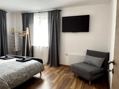a bedroom with a bed and a chair and a television at Green Villa in Saparewo