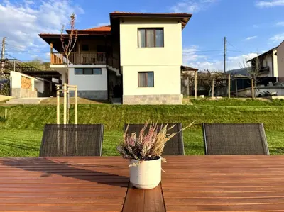 a wooden table with chairs and a vase with flowers on it at Green Villa in Saparewo
