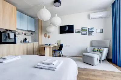 a bedroom with a bed and a chair and a kitchen at New Studio - 300m Subway - 10 Mins City Centre in Sofia