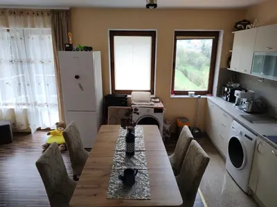 a kitchen with a wooden table and chairs in a room at Апартамент за гости Виктория in Chepelare
