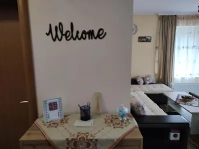 a room with a bed and a welcome sign on the wall at Апартамент за гости Виктория in Chepelare