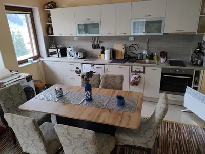a kitchen with a wooden table and chairs at Апартамент за гости Виктория in Chepelare