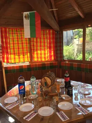 a wooden table with plates and glasses and a flag at Белевската къща с беседка Belevska House with gazebo in Smolyan