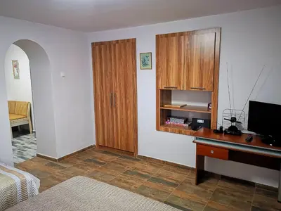 a room with a desk and a cabinet and a television at Студио за гости - Лили in Ognyanovo