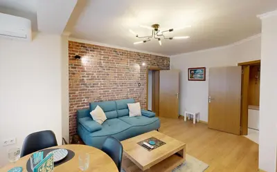 a living room with a blue couch and a brick wall at Апартамент в топ център София 5 Corners in Sofia