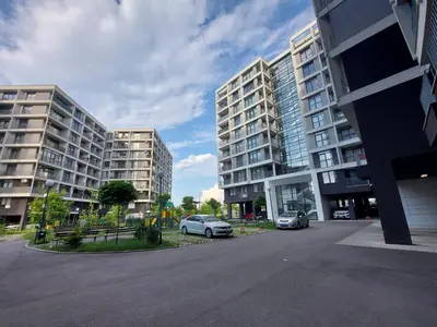 two tall buildings with cars parked in a parking lot at INTER EXPO APARTMENT in Sofia