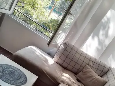 a living room with a couch and a window at Sofia Zen - on Metro, ultra fast Wi-Fi in Sofia