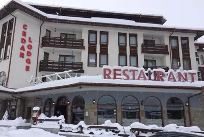 a building with a sign for a restaurant in the snow at Studio in Cedar Lodge 3 in Bansko