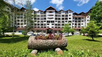 a large building with a flower pot in the grass at Premium StudioApartment in Borovets Gardens in Borovets