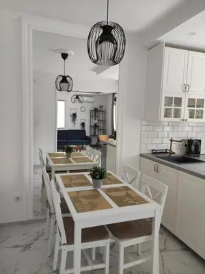 a white kitchen with a table and white chairs at Wellnesshouse Müller in Ilindentsi