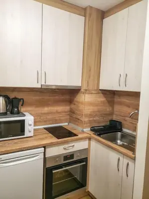 a kitchen with white cabinets and a stove and a sink at Studio A10 Borovets gardens in Borovets
