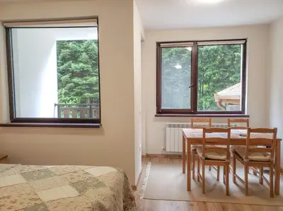 a bedroom with a table and chairs and two windows at Studio A10 Borovets gardens in Borovets