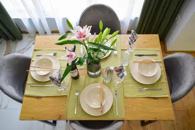 a wooden table with plates and flowers on it at Modern & Elegant City Center Apartments in Plovdiv