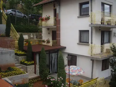 a building with balconies and an umbrella in front of it at Guest House Rusalka in Shipkovo
