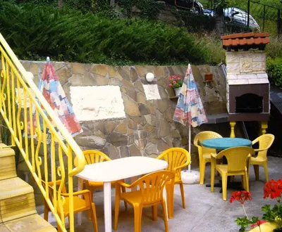 a patio with tables and chairs and a fireplace at Guest House Rusalka in Shipkovo