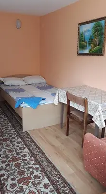 a bedroom with two beds and a table and a chair at Guest House Rusalka in Shipkovo