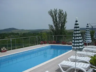 a swimming pool with lounge chairs and an umbrella at Apartments in Relax Complex Fantasy in Hisarya