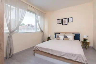 a white bedroom with a large bed and a window at Cozy home next to Aliosha - Boho Stay in the heart of Plovdiv in Plovdiv