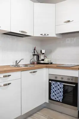 a kitchen with white cabinets and a sink and a stove at Cozy home next to Aliosha - Boho Stay in the heart of Plovdiv in Plovdiv