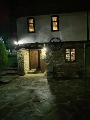 an old stone building with windows and a wheel on it at Къща за гости КИМ in Apriltsi