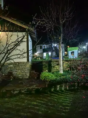 a house with a tree in a yard at night at Къща за гости КИМ in Apriltsi