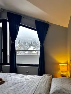 a bedroom with a bed and a large window at Мансарда с фантастични гледки и две спални in Chepelare