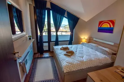 a bedroom with a bed with a rainbow painting on the wall at Мансарда с фантастични гледки и две спални in Chepelare