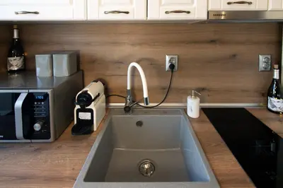 a kitchen counter with a sink and a microwave at Мансарда с фантастични гледки и две спални in Chepelare