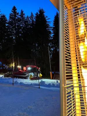 a snow truck is parked in the snow at night at STENATA Sport Apartments in Pamporovo