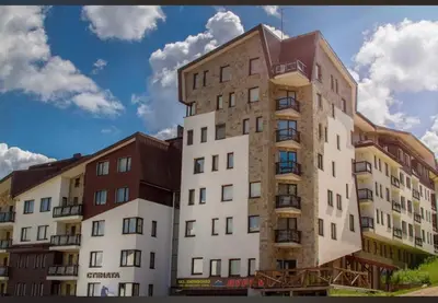 a tall building in front of two other buildings at STENATA Sport Apartments in Pamporovo
