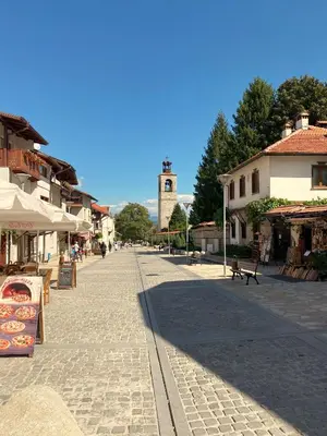 a street in a town with a clock tower in the distance at Belvedere Holiday Club H41 in Bansko