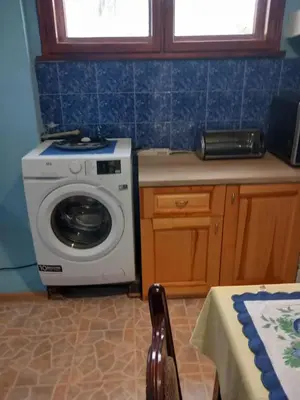 a kitchen with a washing machine and a table at Къща за гости Дани in Govedartsi