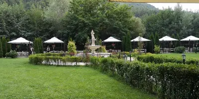 a park with a fountain and tables and umbrellas at Апартамент и Студия 