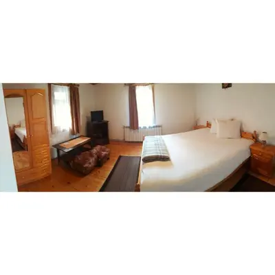 a bedroom with a large white bed and wooden floors at Sarafova Guest House in Koprivshtitsa